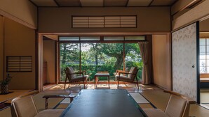 Une pièce de style japonais traditionnel, avec un sol recouvert de tatamis, une table basse et des sièges pour quatre personnes.