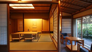 Une pièce de style japonais traditionnel, avec un sol recouvert de tatamis, une table basse et une porte coulissante donnant sur un jardin.