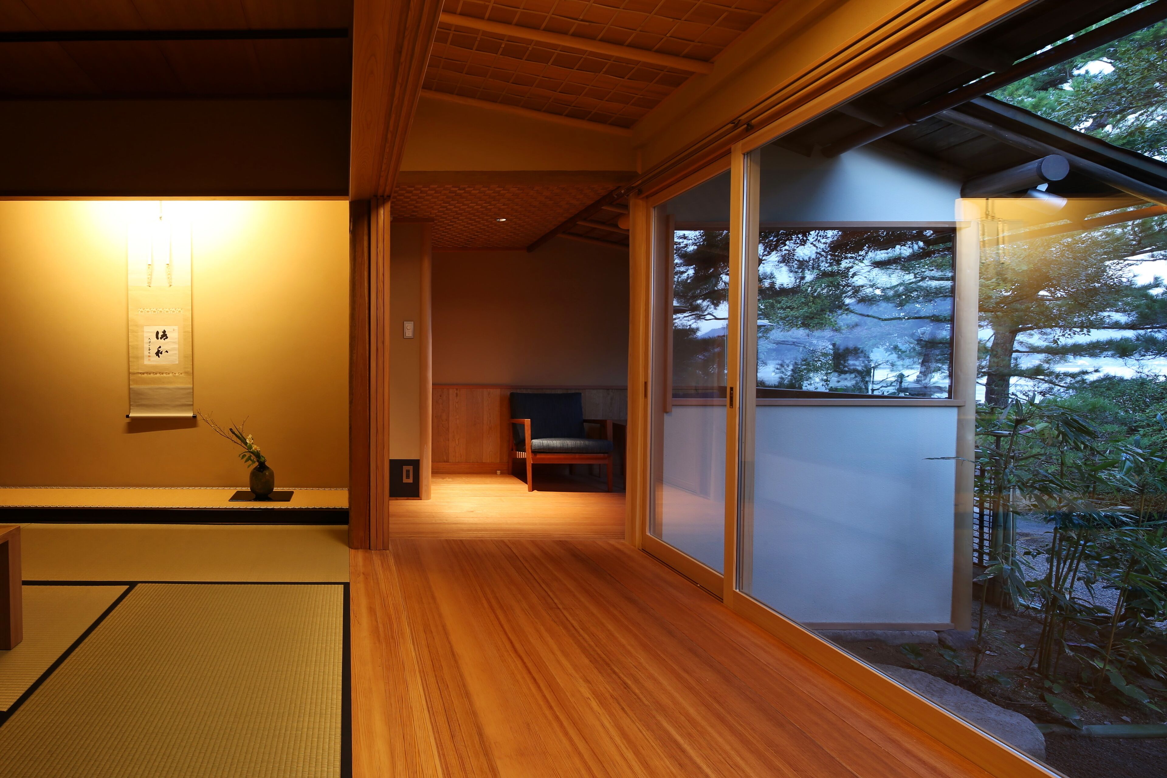 A traditional Japanese interior with tatami flooring, sliding doors, and a view of a snowy landscape.