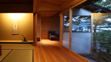 A traditional Japanese interior with tatami flooring, sliding doors, and a view of a snowy landscape.