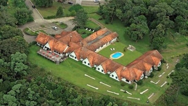 A large, thatched-roof building with multiple rooms, a swimming pool, and a well-maintained lawn. - Hotel Pousada João de Barro (Rio Negrinho)