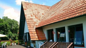A wooden deck with outdoor seating and a building with a sloped roof. - Hotel Pousada João de Barro (Rio Negrinho)