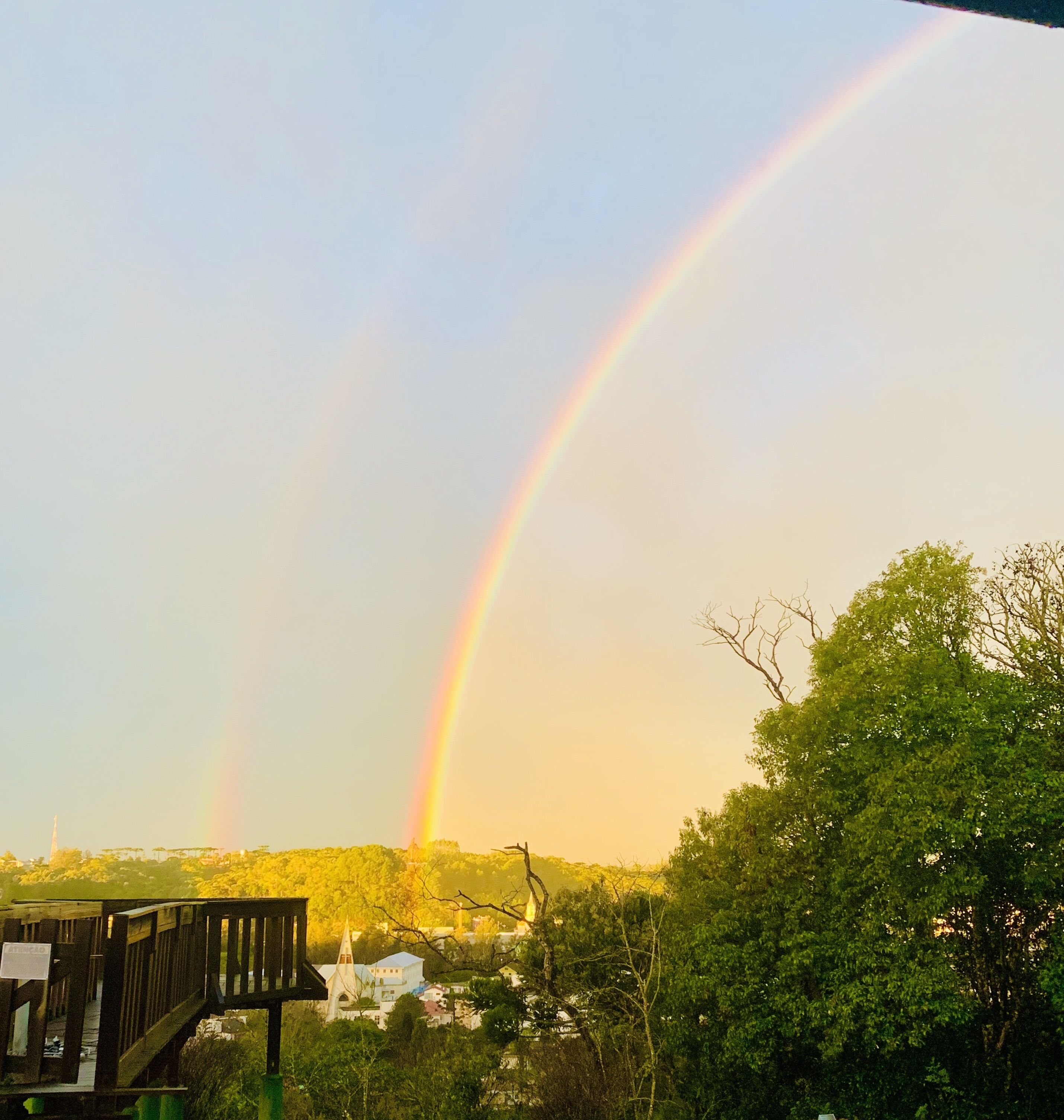Um arco-íris sobre um bairro residencial com casas e um deck de madeira.