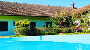 A swimming pool with a house in the background. - Hotel Pousada João de Barro (Rio Negrinho)