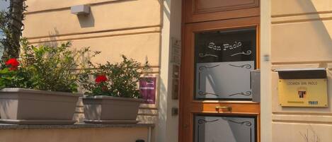 A hotel entrance with a red carpet, a wooden door with a sign reading "San Paolo," and a plaque indicating "Locanda San Paolo."