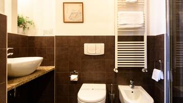 Un baño moderno con un lavamanos grande, inodoro, bidé y toallero.