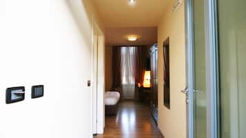 Ein Hotelkorridor mit einem Bett, einem Schreibtisch und einer Glastür.