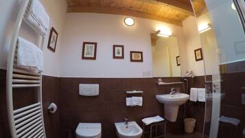 A bathroom with a toilet, bidet, sink, and towel rack.