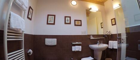 Un baño con inodoro, bidé, lavamanos y toallero.