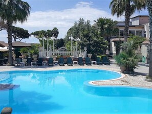 A swimming pool with lounge chairs and palm trees. - Hotel Orchidea (Giugliano in Campania)