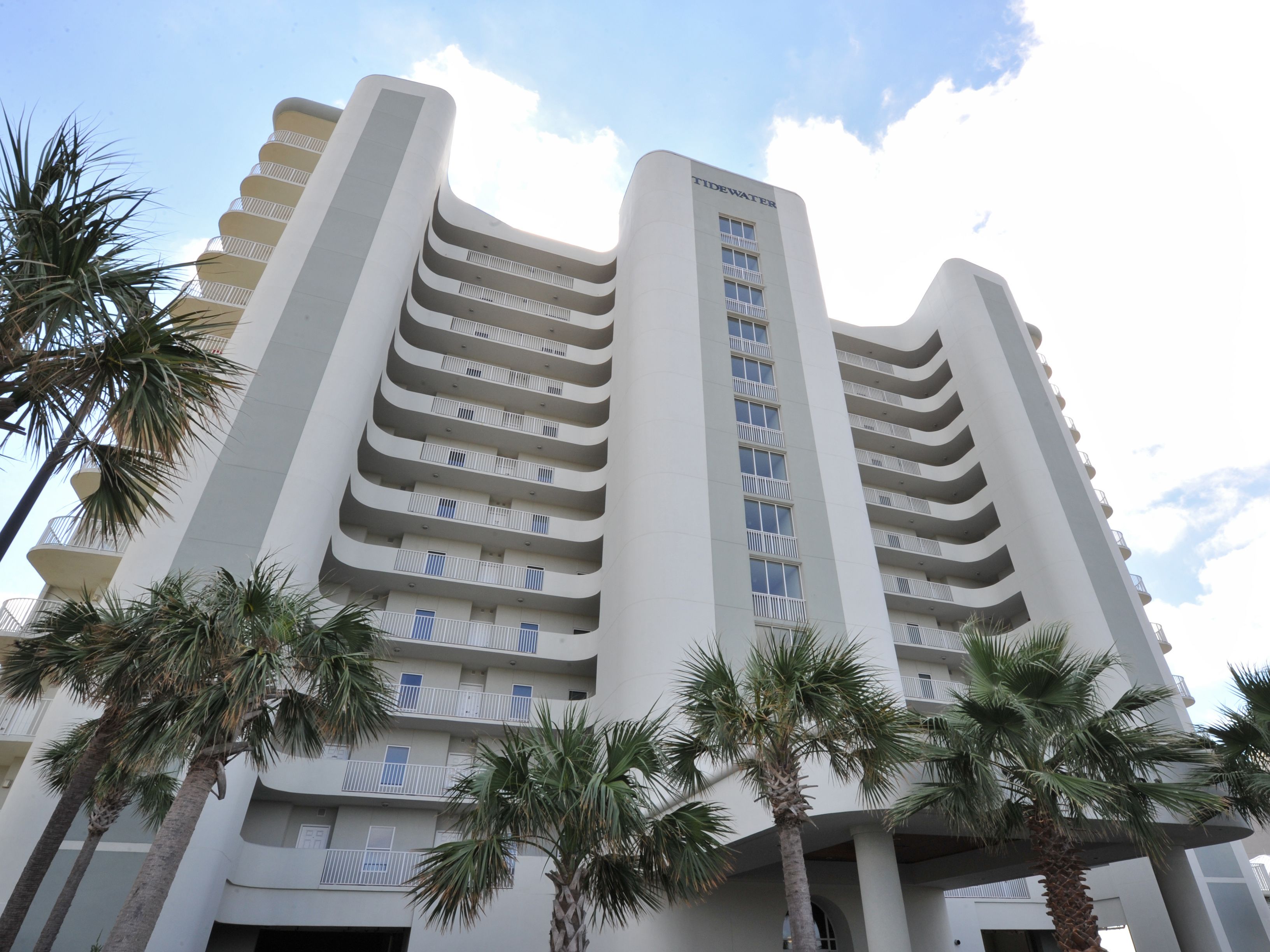 A multi-story hotel with a modern design, featuring balconies on each floor and a prominent 'Tidewater' sign.