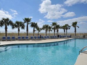 A swimming pool with blue lounge chairs and palm trees. - Tidewater By Wyndham Vacation Rentals (Orange Beach)