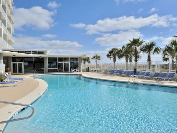 A swimming pool with blue lounge chairs and palm trees. - Tidewater By Wyndham Vacation Rentals (Orange Beach)