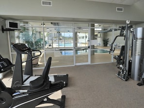 A gym with exercise equipment, a pool, and a view of the outside.