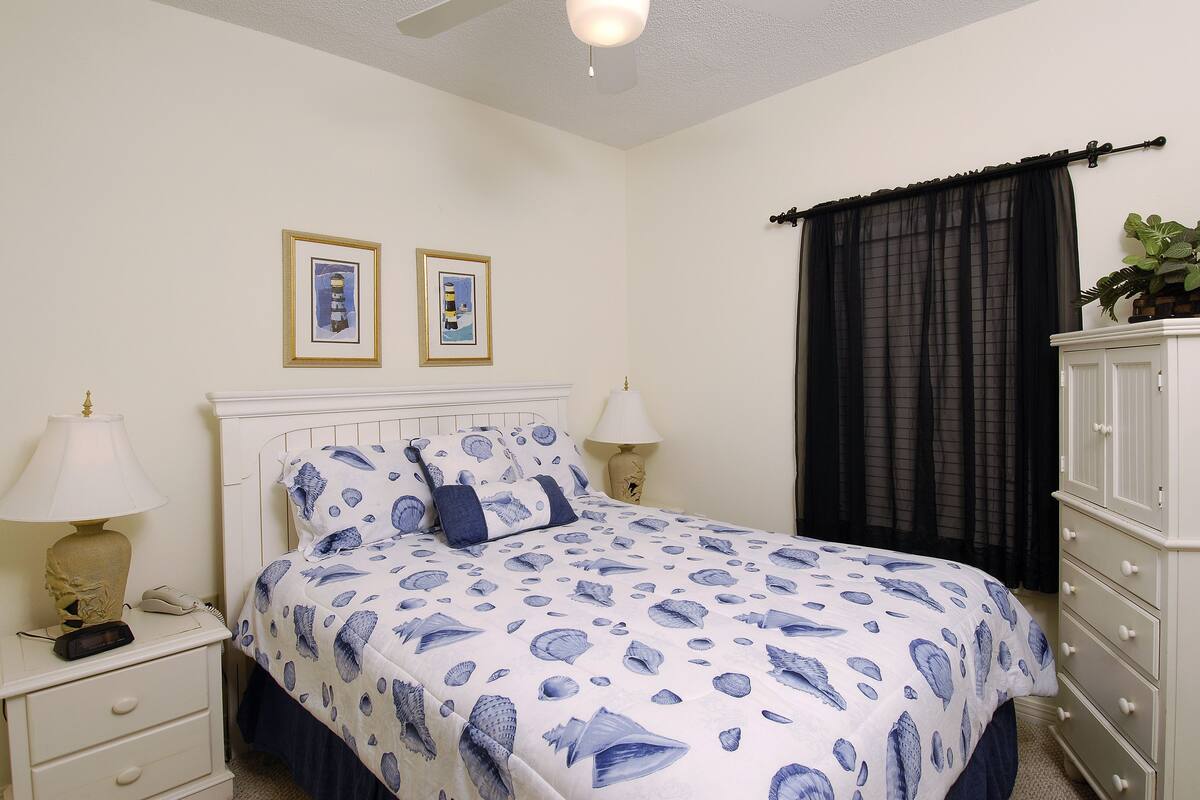 A bedroom with a bed, two bedside tables, a nightstand, a dresser, and a ceiling fan.