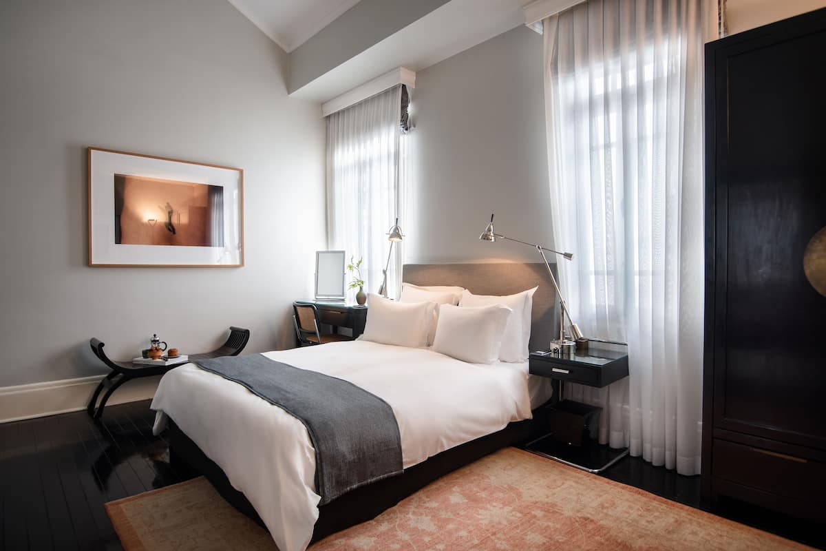 Quarto de hotel com uma cama grande, mesas de cabeceira, uma escrivaninha e uma cadeira.