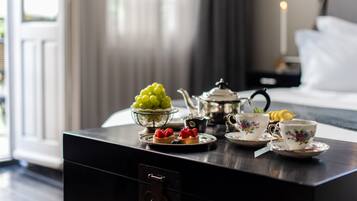 A neatly arranged table with a teapot, cups, and a bowl of fruit.
