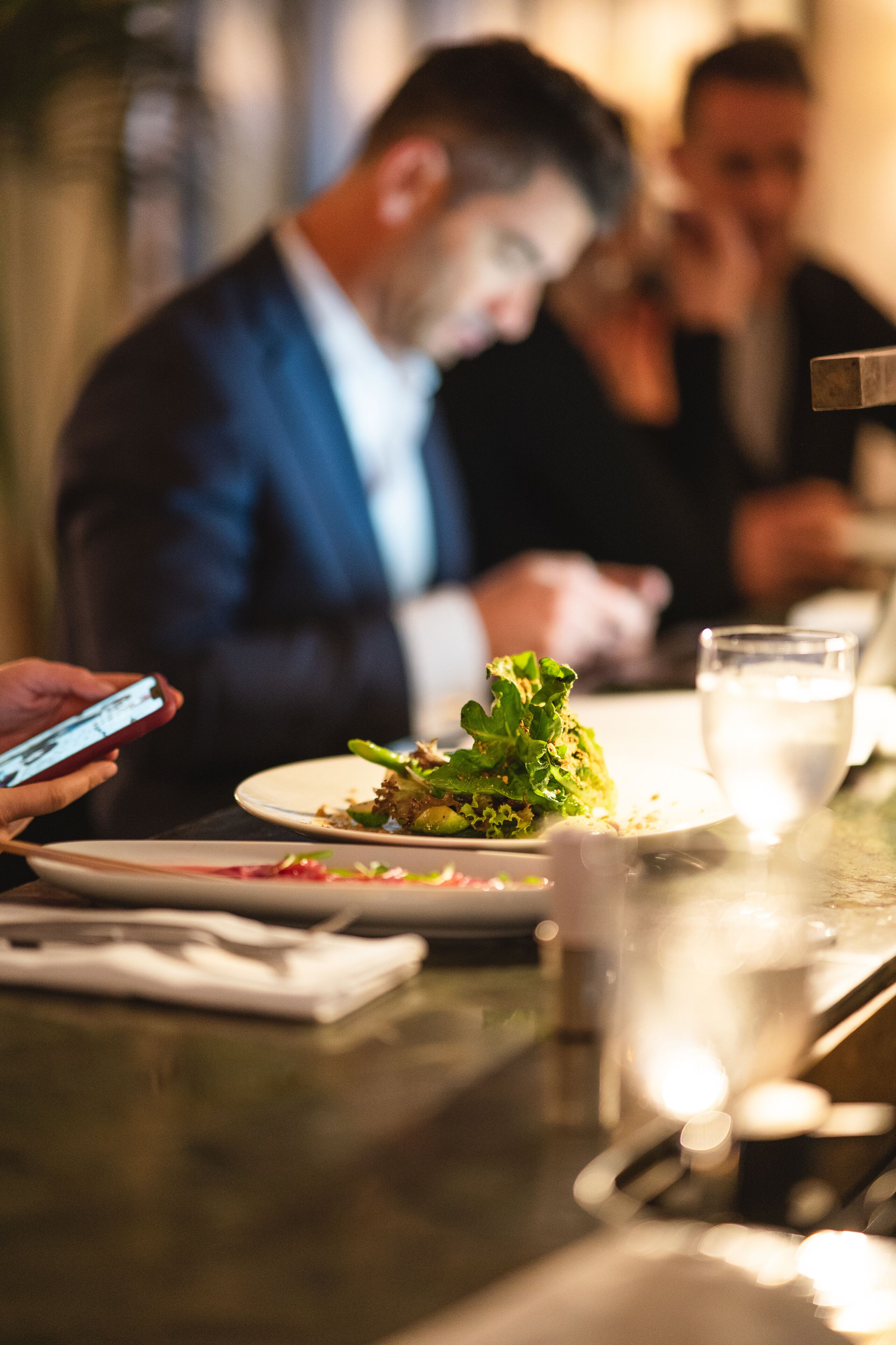 Una mesa con platos de comida, un vaso de agua y un teléfono inteligente.