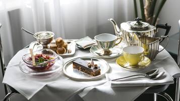 A table set with a variety of food items, including a dessert, a bowl of fruit, and a teapot.