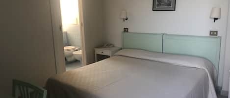 A bedroom with a bed, bedside tables, a chair, a mirror, and a picture on the wall.