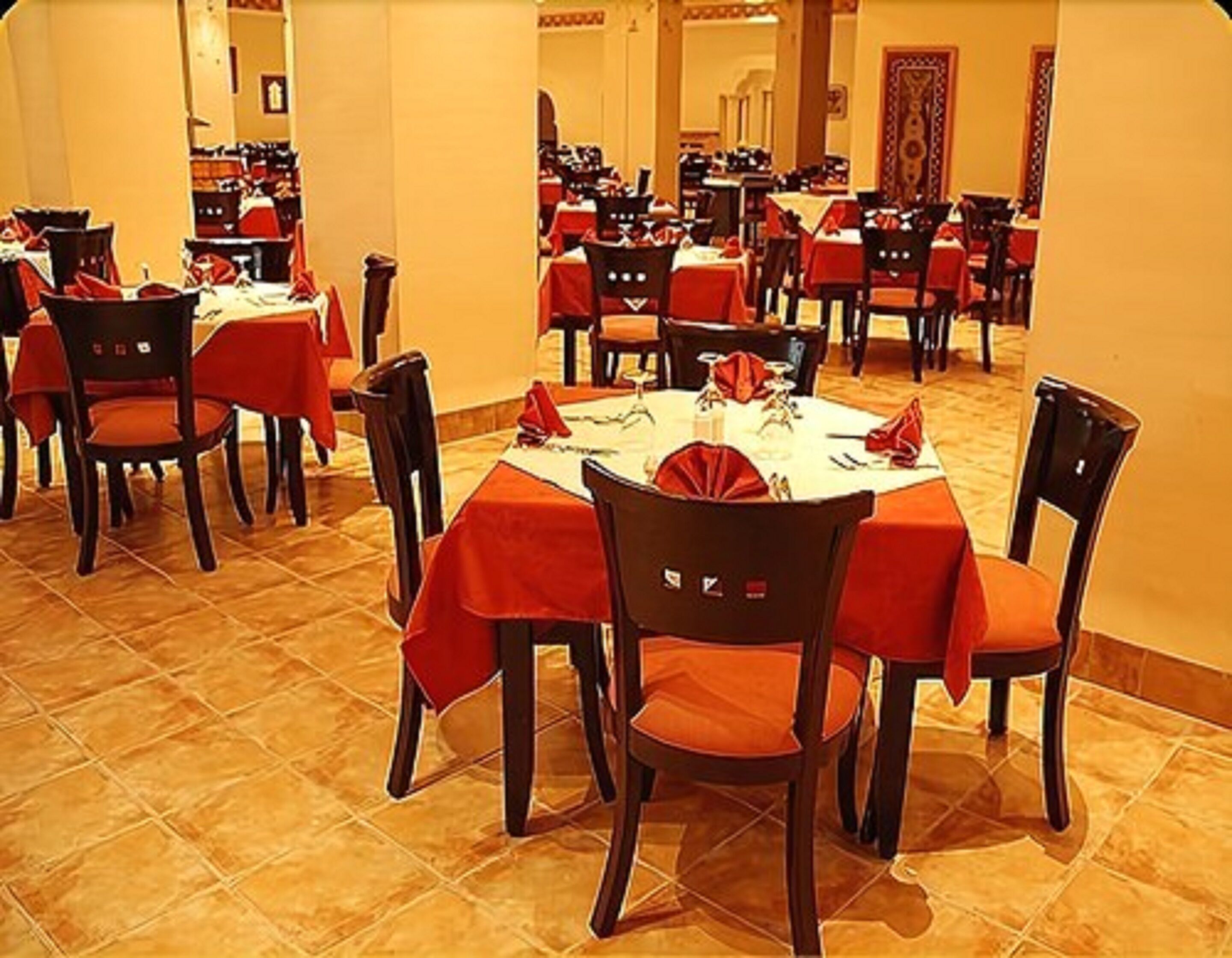 Ein Restaurant mit mehreren runden Tischen, bedeckt mit roten Tischdecken und Holzstühlen.