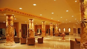 A spacious lobby with high golden columns, comfortable seating, and a polished floor. - Hotel Sahara Douz (Douz Nord)