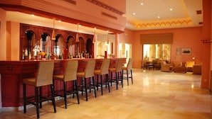 A bar area with a row of wicker chairs, a polished marble floor, and a warm color scheme. - Hotel Sahara Douz (Douz Nord)