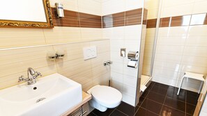 Un baño con lavamanos, inodoro y zona de ducha.