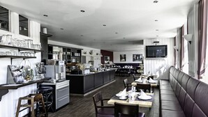 A modern restaurant with a central island, bar stools, and a long dining table with chairs. - Art Hotel Monopol (Gelsenkirchen)