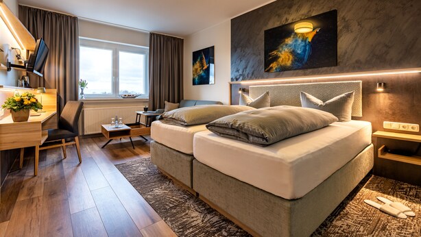 A modern hotel room with a large bed, a desk with a computer, a small table, and a window with curtains. - Art Hotel Monopol (Gelsenkirchen)
