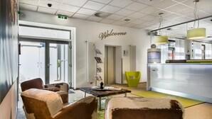Un interior moderno con un letrero que dice 'Welcome', una recepción y zonas de estar.