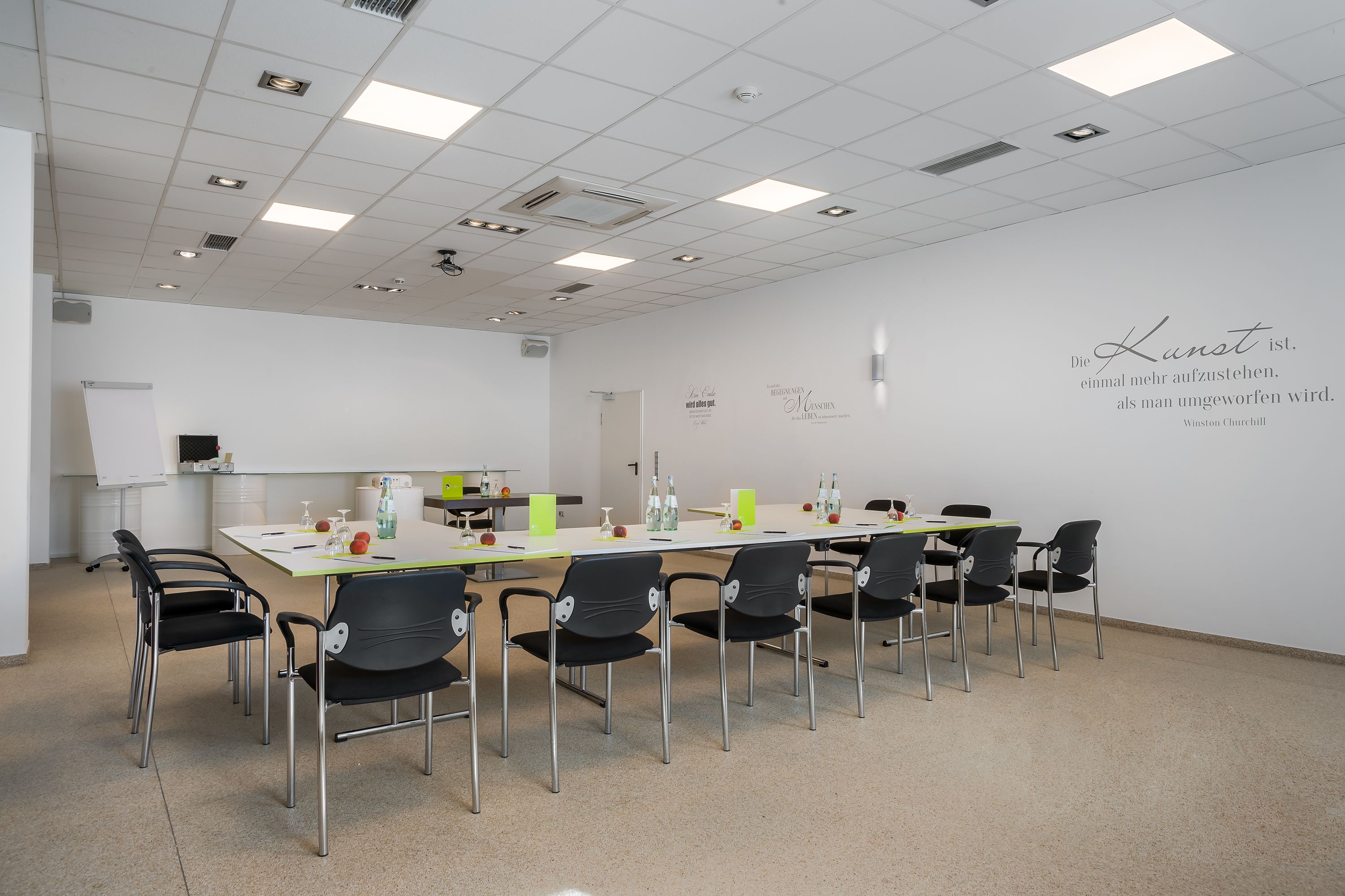 Una sala de conferències amb una taula llarga, caires negres i una pissarra.