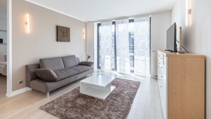 Una sala de estar moderna con un sofá gris, una mesa de centro blanca y un armario de madera.