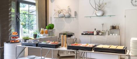 Una cocina moderna con servicio de comidas tipo buffet, que incluye frutas, verduras y diversos platos.