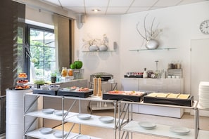 Una cocina moderna con servicio de comidas tipo buffet, que incluye frutas, verduras y diversos platos.