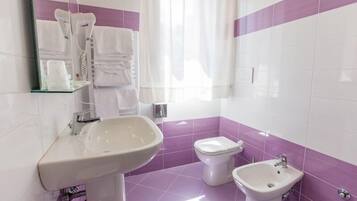 Un baño con lavamanos, inodoro, bidé y espejo.