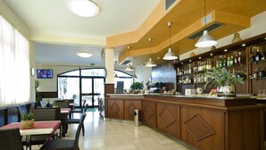 A bar area with wooden cabinets, hanging lights, and a variety of bottles. - Villa Hotel del Sole (Chiusi)