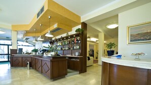 A bar area with a wooden counter, shelves of bottles, and a potted plant. - Villa Hotel del Sole (Chiusi)