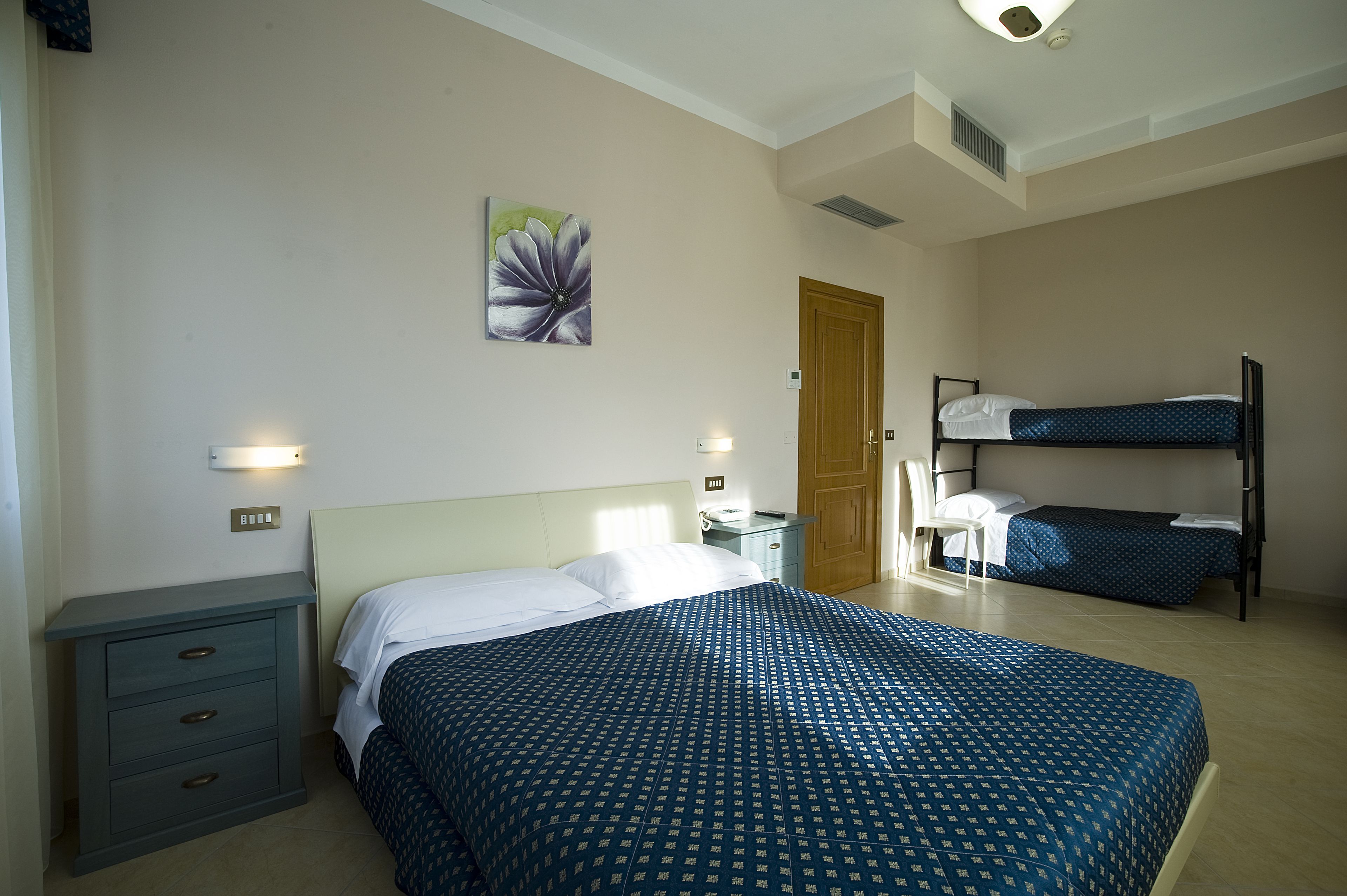 A bedroom with a large bed, a smaller bed, a nightstand, a dresser, and a painting on the wall.