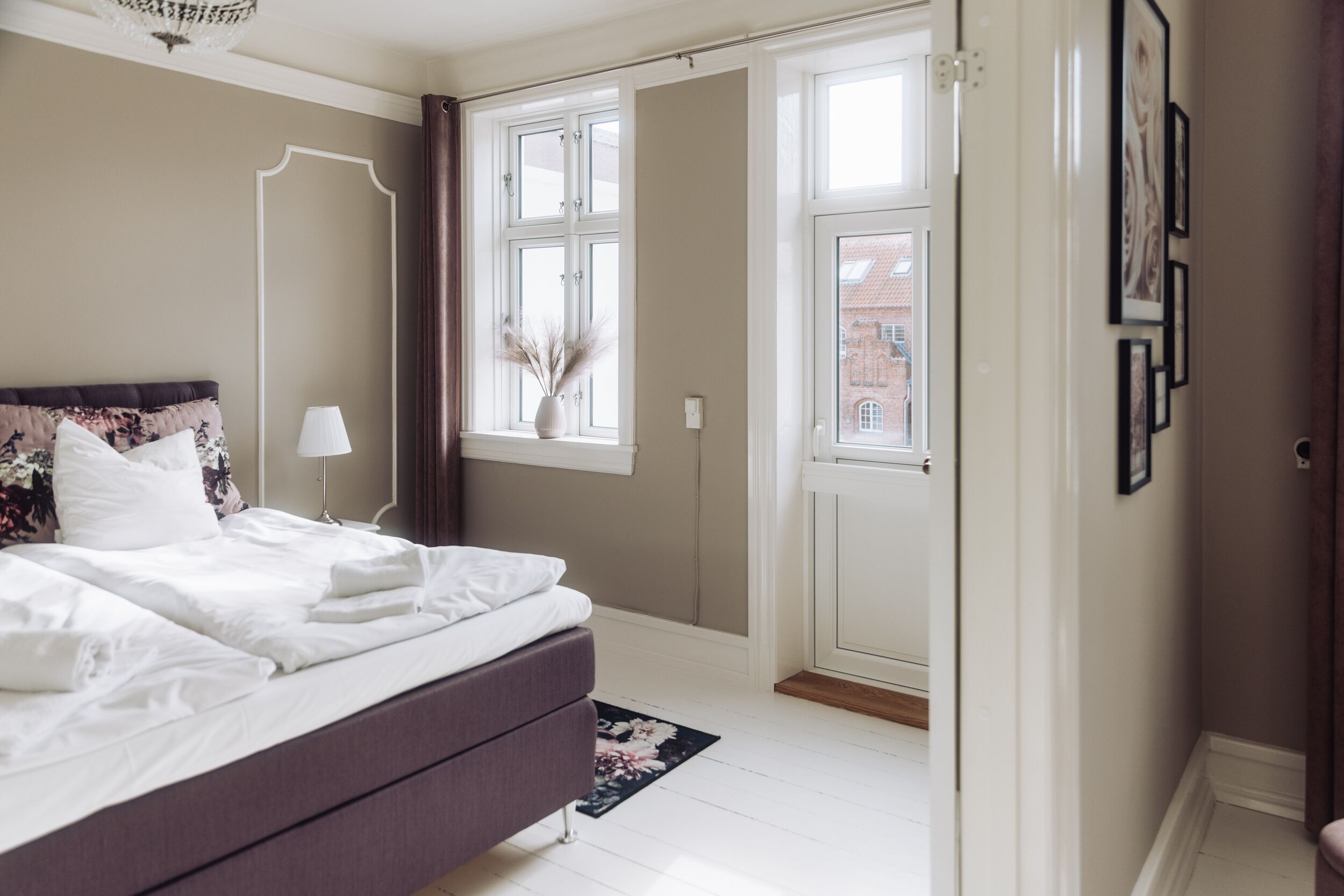 A bedroom with a bed, a nightstand, a window, and a door.