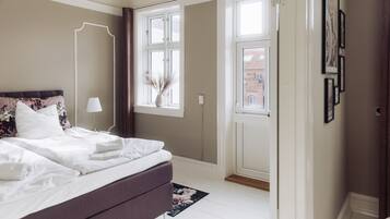 A bedroom with a bed, a nightstand, a window, and a door.