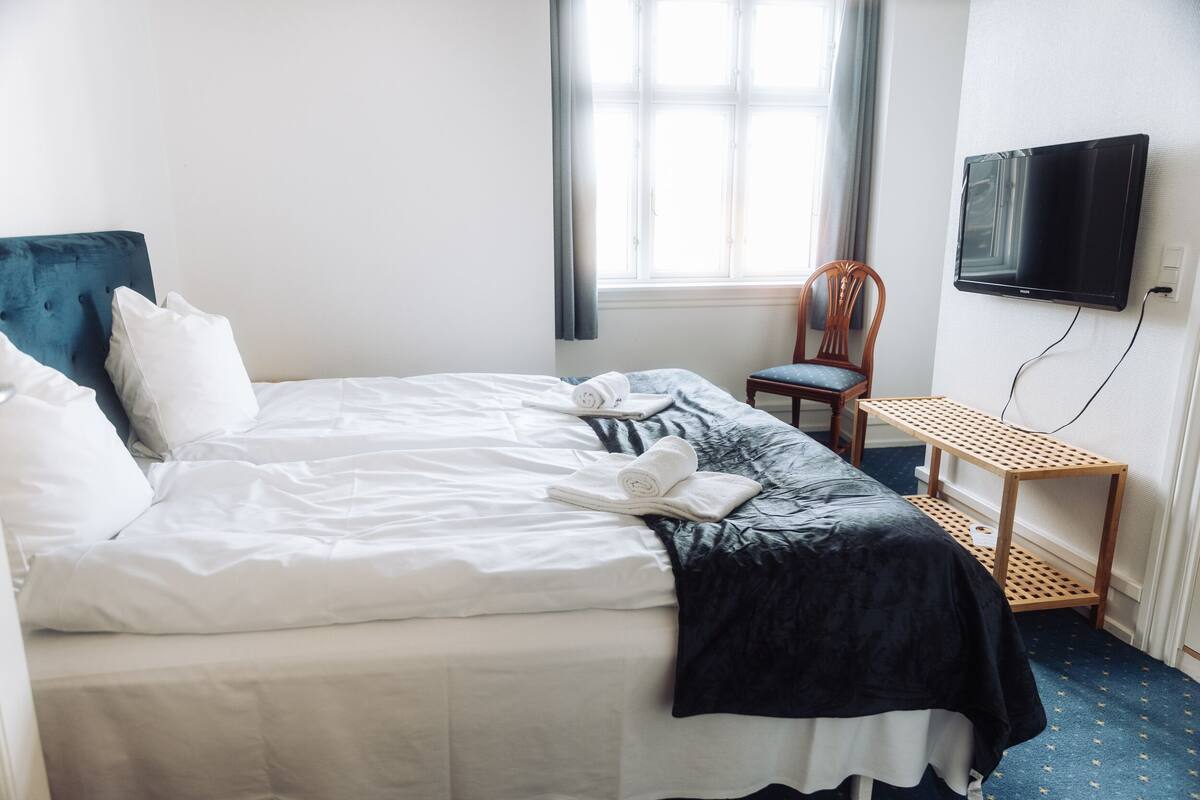 A hotel room with a bed, a chair, a TV, and a small table.