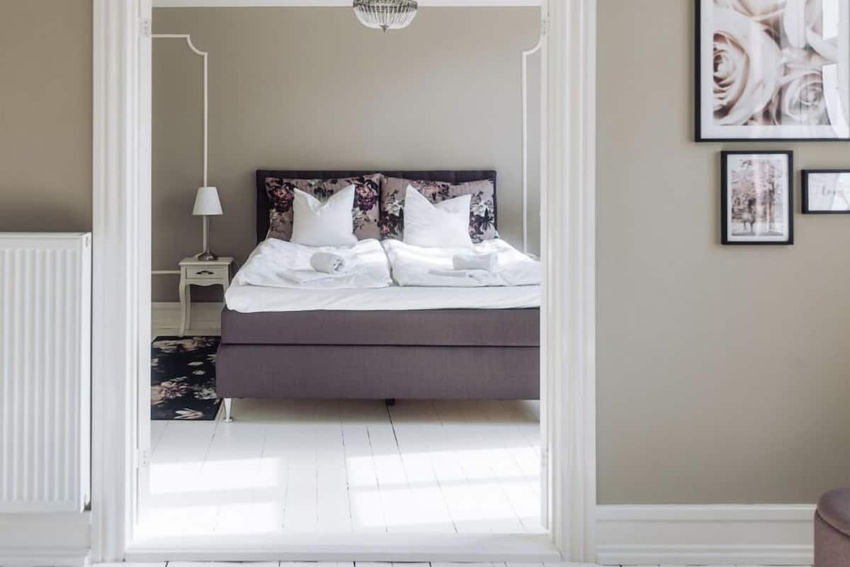 A bedroom with a bed, a nightstand, a lamp, and framed pictures on the wall.