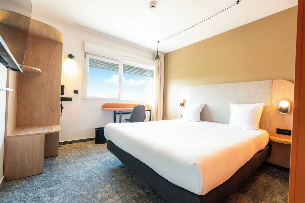Una habitación de hotel con una cama grande, un escritorio y una silla.