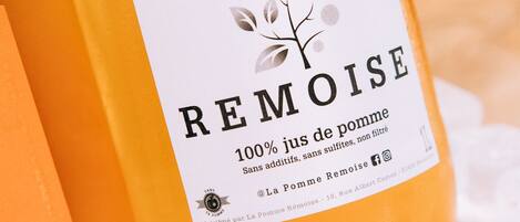 A bottle of La Pomme Rémoise 100% jus de pomme with a label indicating it is distributed by La Pomme Rémoise and contains no additives or sulfites.