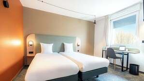 Habitación de hotel con dos camas, un escritorio y una computadora.