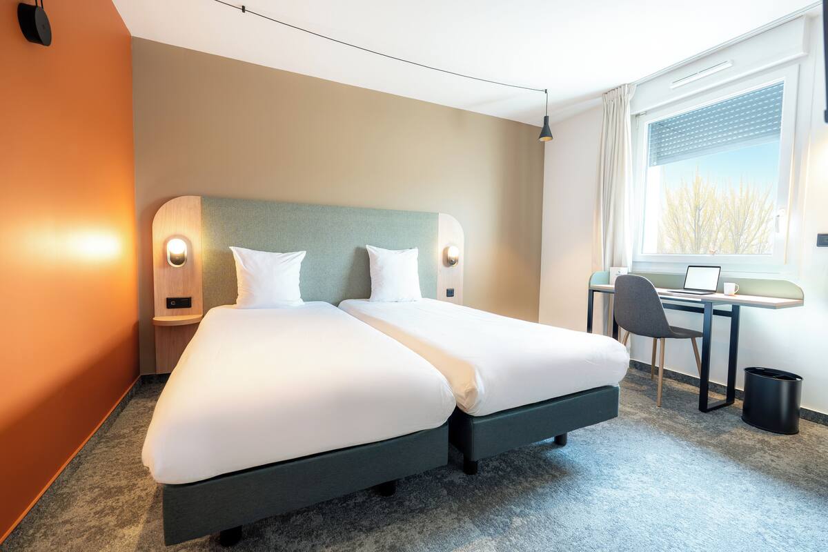 Habitación de hotel con dos camas, un escritorio y una computadora.