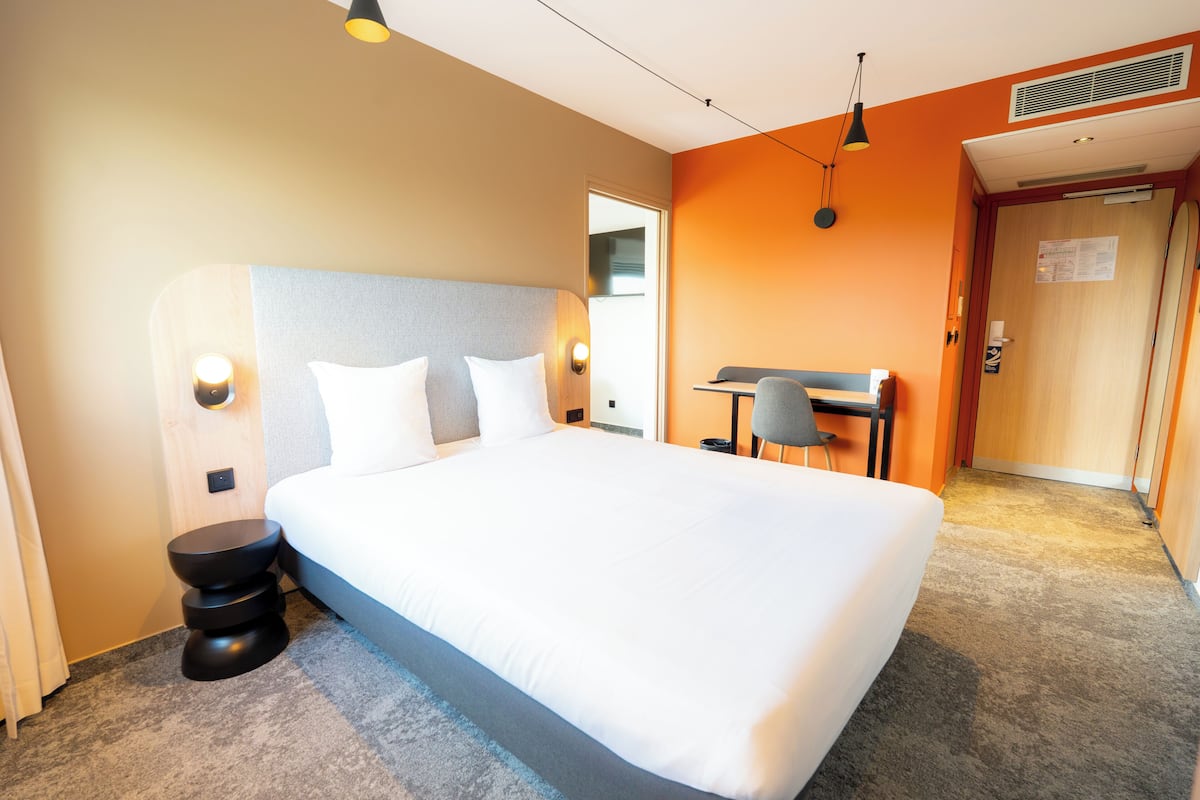 Una habitación de hotel con una cama grande, una mesita de noche y un escritorio con una silla.