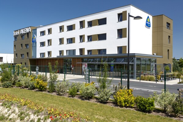 Un hôtel moderne à la façade sobre, doté de nombreuses fenêtres et d’une entrée bien visible.