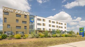 Un hotel llamado AKENA, con un diseño de edificio moderno, varias plantas y fachada de vidrio.
